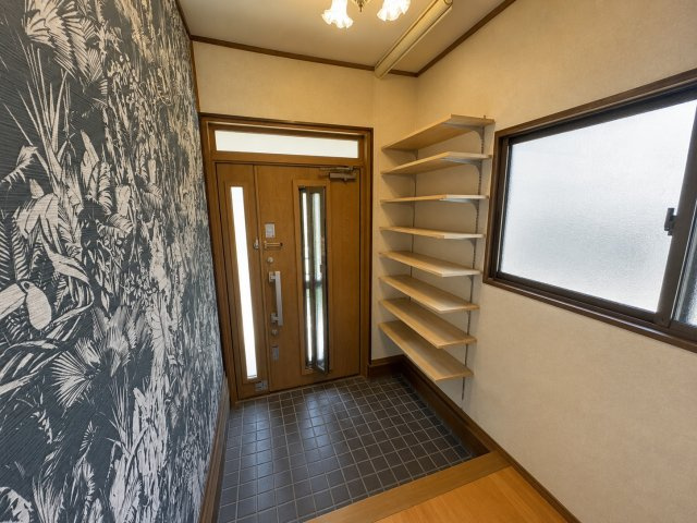 アクセントクロスが印象的な玄関スペースは住まいの第一印象をおしゃれに演出します。採光窓付きの玄関ドアから自然光が入り明るく開放感のある空間です。可動棚収納も備わっており靴や小物類をすっきり整理できます