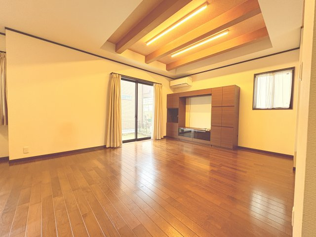 折上げ天井と間接照明が印象的なリビング空間。天井に高さと奥行きを持たせることで、実際の広さ以上の開放感を感じられます。大きな掃き出し窓からは自然光がしっかり入り、明るく心地よい空間を演出。