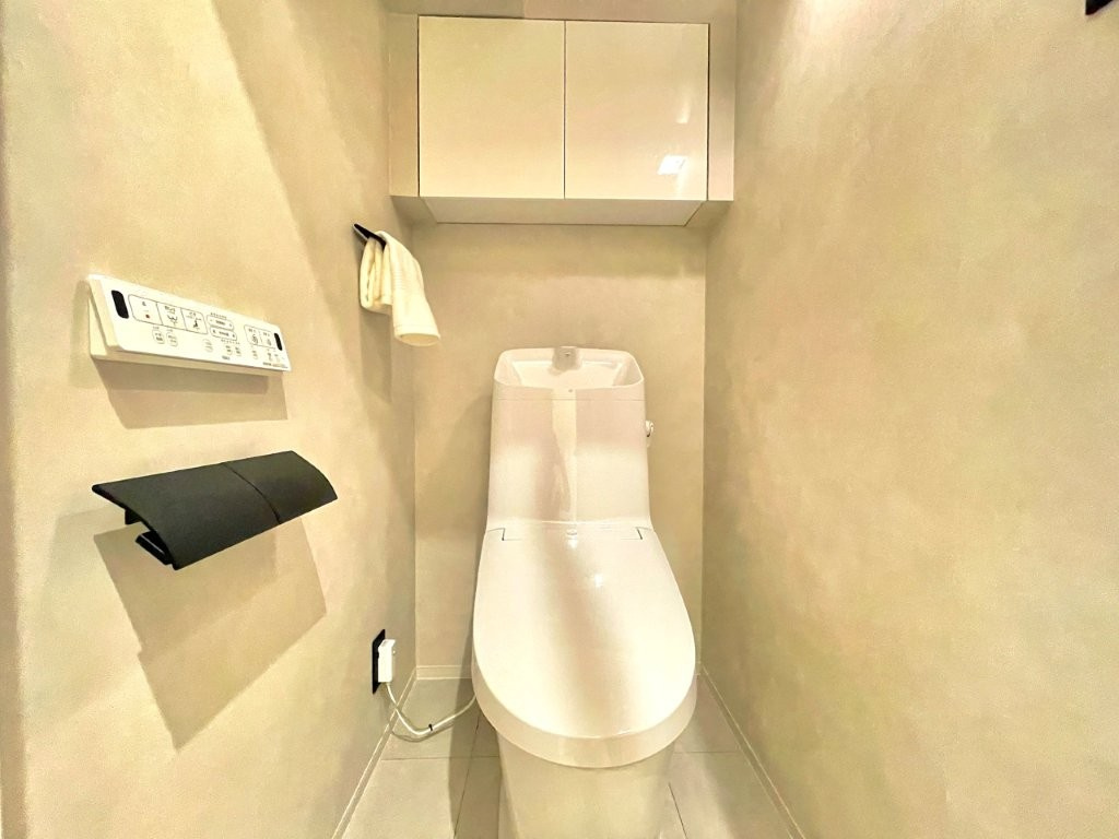 明るく清潔感溢れるトイレです。温水洗浄便座付きで、季節を問わずいつでも温かい便座をお使いいただけます。トイレットペーパーのストックや消耗品置き場などとしてお使いいただける吊戸棚がございます。