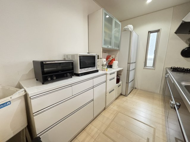 キッチン背面には大型のキャビネットを設置。引き出し収納で出し入れしやすく家電や食器、調理器具をすっきり整理できます。上部のガラス扉付き収納は中身が見やすく清潔感ある印象に。日々の家事を快適にサポート。