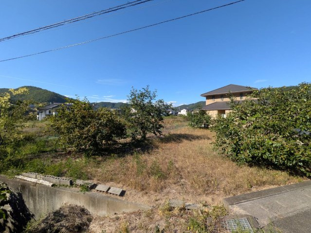 開放感のある現地の様子です。周辺には低層の住宅が建ち並び、その先には緑豊かな山々を望む、自然を感じられる環境が広がっています。敷地は約84坪とゆとりがあり、住宅用地として幅広いプランを検討可能。