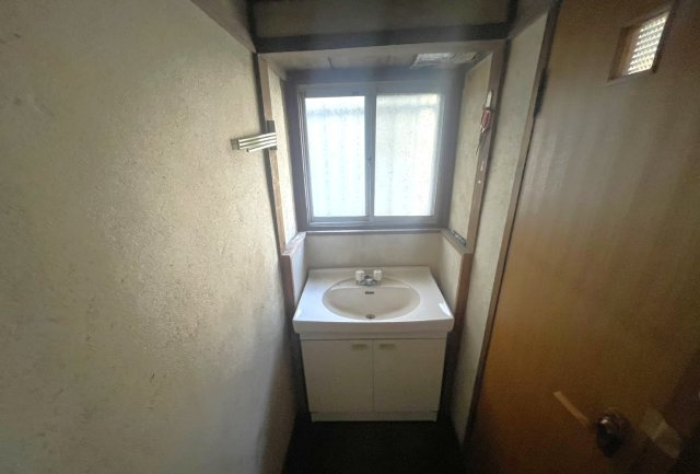 窓付きで自然光が入る明るい洗面スペース。コンパクトながらも使いやすい洗面台を備え、朝の身支度や帰宅後の手洗いにも便利。上下に収納があり、洗剤やタオル類もすっきり整理可能。廊下から直接アクセスできます。