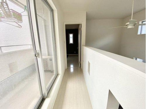 2階の渡り廊下は、バルコニーに面した大きな窓があり採光も良好。吹き抜けを見下ろす開放的な空間で、家全体のつながりを感じられる明るい通路です。