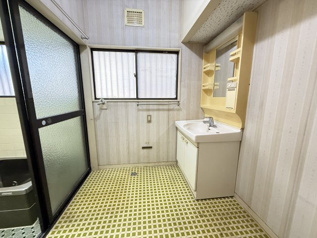 大きな鏡付き洗面台は収納棚も備わり、日用品を整理しやすい設計です。窓から光が差し込むため明るく、換気もしやすい環境。洗濯機置き場も隣接しており、家事動線がスムーズに整った実用的な空間となっています。　