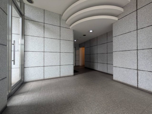 石調の壁面と曲線を描く天井デザインが印象的なマンションエントランス。落ち着いた色合いでまとめられすっきりした上品な雰囲気です。住まいの顔となる共用部分にもゆとりが感じられ出入りを心地よく迎えてくれます