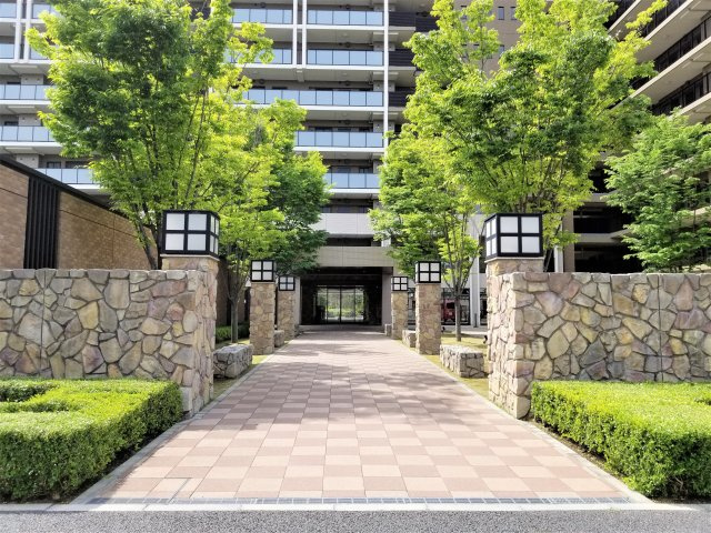 住まう方を優雅に迎える美しいアプローチ「ベルパサージュ」　石積みのゲートでで演出されたゲートの向こうに広がる瑞々しいケヤキ並木が、上質なステイタスと品格を感じさせます。