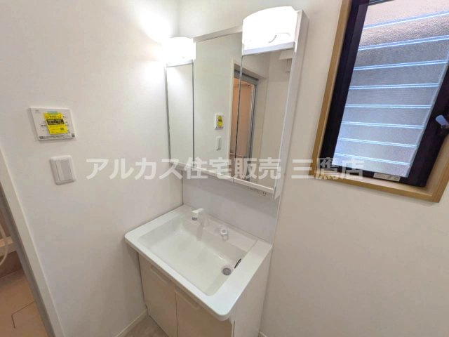 三面鏡付き洗面化粧台と小窓を備え、身支度や換気に配慮された洗面室です。
