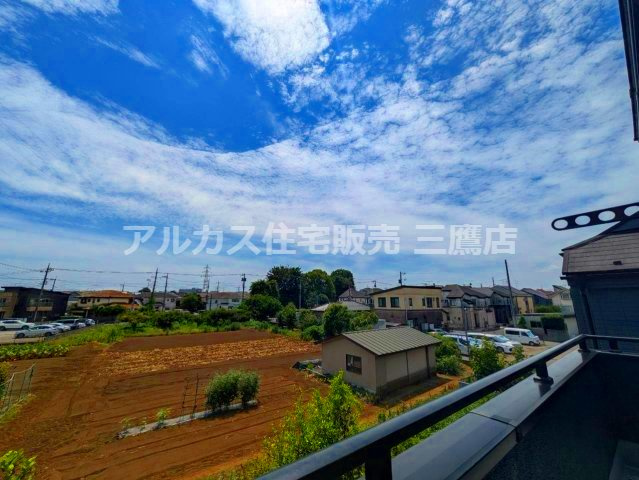 バルコニーから、畑や低層の街並み、広がる空を見渡せる眺望です。