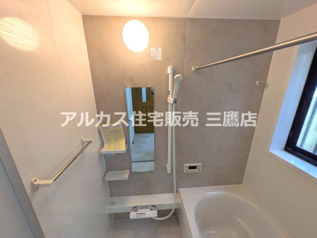 グレーのアクセント壁と窓が印象的な、物干しバーを備えた浴室です。