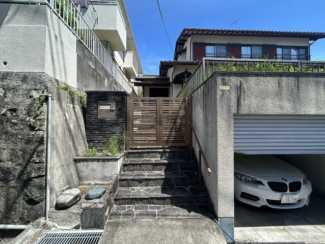 シャッター付きガレージを備え、大切なお車を雨風や紫外線から守ります。門扉付きのアプローチはプライバシーや防犯面にも配慮。高台ならではの開放感と落ち着いた住環境が魅力の戸建住宅です。