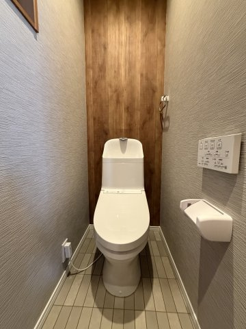 正面の木目調アクセントクロスが落ち着いた雰囲気を演出。手洗い一体型で節水効果が高く、温水洗浄便座や壁掛けリモコン付きで毎日快適に使用できます。