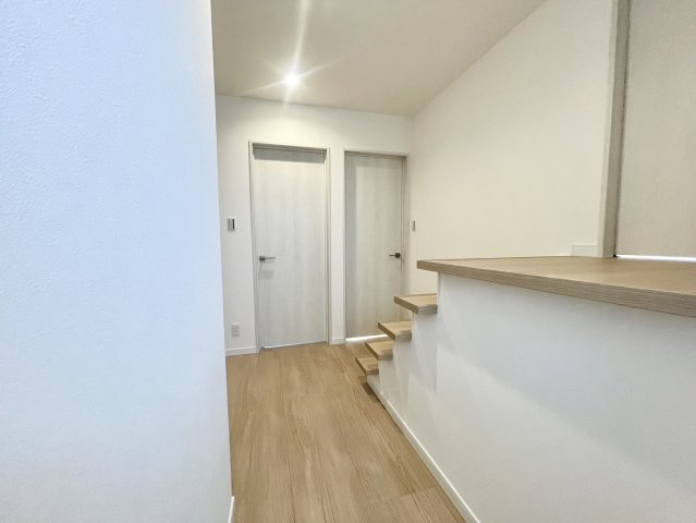 階段上はシンプルでモダンなデザインが特徴。シアタールームへと繋がる動線となっており、特別な時間を楽しむための空間へ移動できます。白を基調とした壁と温かみのある木目調の床が調和し落ち着いた雰囲気を演出。