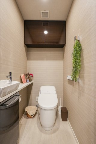空間がスマートに見えるタンクレストイレを採用。手洗いカウンターや吊り戸棚も設置されています。