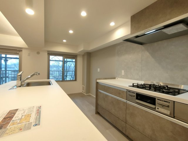 【キッチン】　大型ペニンシュラキッチンを採用。傷や汚れの目立ちにくい人工大理石のキッチン天板、見た目もスマートな薄型レンジフードを採用しています。