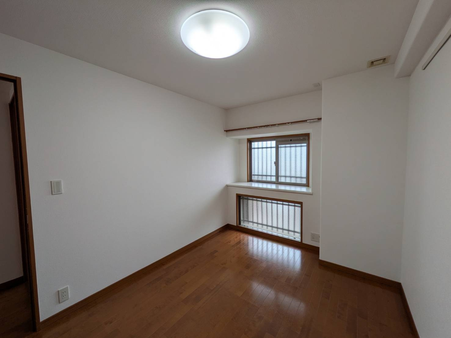 約6帖の洋室は、主寝室としてもゆとりを持って利用できる使い勝手の良い空間です。窓際にはスペースが設けられており、シンプルな間取りで家具の配置もしやすく、ライフスタイルに合わせたお部屋づくりが可能です。