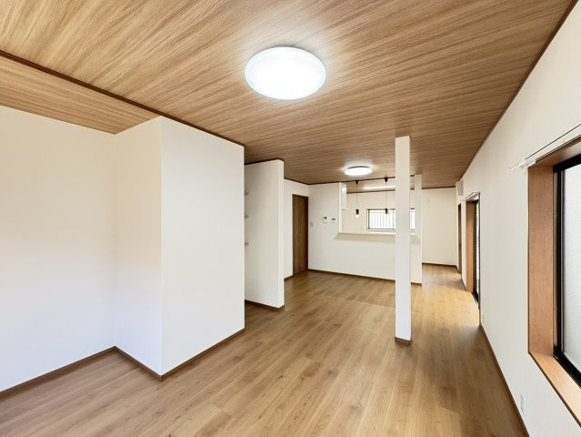 約19.5帖の広々LDKは、ご家族みんながゆったり過ごせる開放感が魅力です。大きな窓から自然光が差し込み、室内全体が明るく心地よい空間に。木目調の天井がアクセントとなり、落ち着きと温かみを感じられます