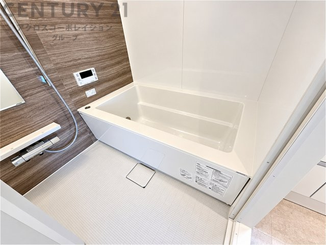 木目調のアクセントパネルが上質な雰囲気を演出する浴室。ゆったりとした浴槽で一日の疲れを癒せます。清潔感のある明るい空間で、毎日のバスタイムを快適にお楽しみいただけます。