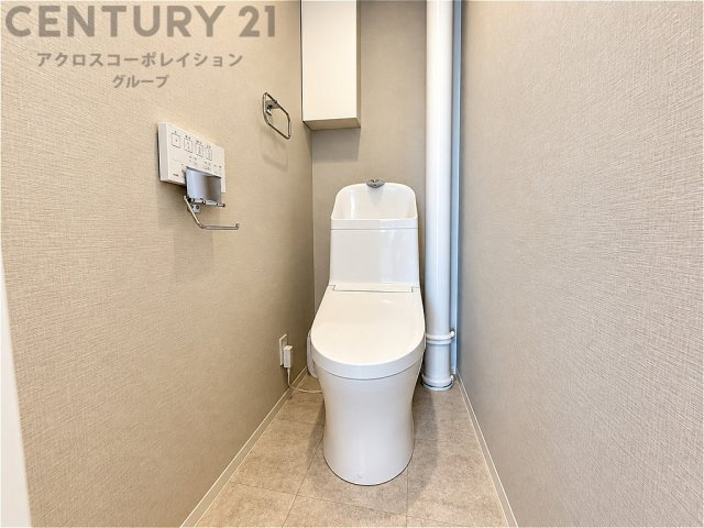 温水洗浄便座を備えた清潔感のあるトイレ。落ち着いた色合いの内装が心地よい空間を演出。収納スペースも備え、すっきりと整理できます。