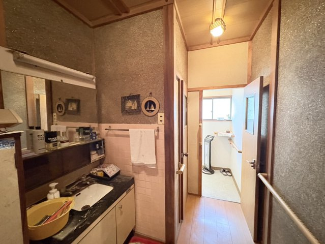 洗面台が設置された水回りスペースで、朝の身支度や日常の手洗いなどに便利な空間です。壁面のタイルやカウンターが使いやすく、収納棚も設けられているため日用品の整理にも役立ちます。生活の中で使いやすい配置。