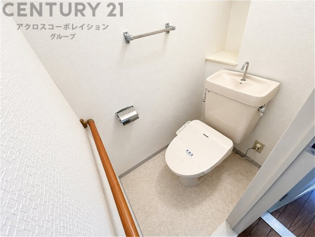 清潔感のある明るいトイレ空間。温水洗浄便座を備え、手洗いスペースも確保されています。手すり付きで立ち座りをサポートし、毎日快適にお使いいただけます。
