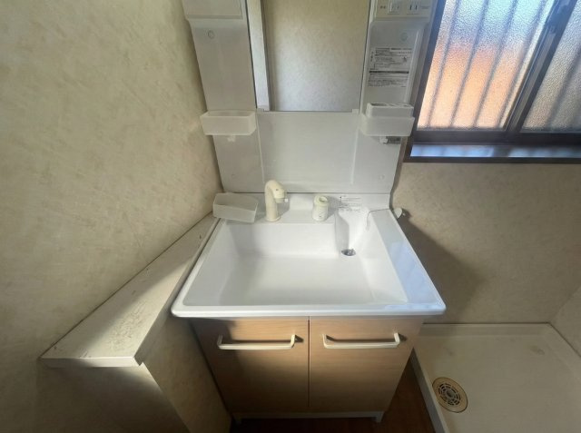 使いやすいサイズの独立洗面台。鏡横には小物収納スペースがあり、歯ブラシや整髪料なども整理しやすい設計です。下部収納も備わっているため洗剤やストック用品の収納にも便利。窓があり自然光が入ります。