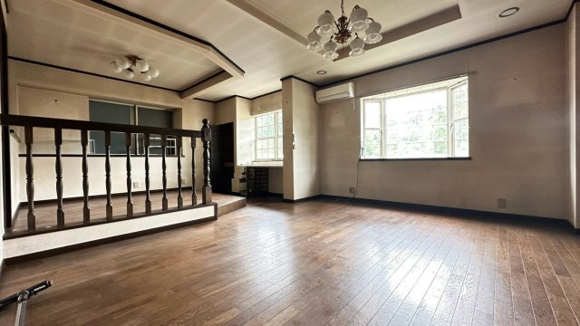 【出窓と折上天井が映える広々リビング】クラシカルな照明と印象的な出窓が落ち着いた空間を演出。ステップで緩やかに区切られたダイニングもあり、ご家族でゆったり寛げる開放的なリビングです。