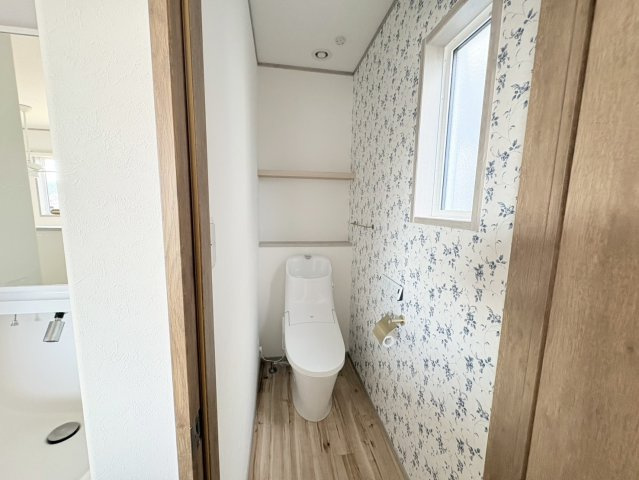 洗面スペースのすぐ隣に配置された2階トイレは、生活動線の良さが魅力。花柄のクロスが空間を明るく彩り、清潔感とおしゃれさを演出しています。カウンター付きで小物の置き場にも便利な使い勝手の良いトイレです。