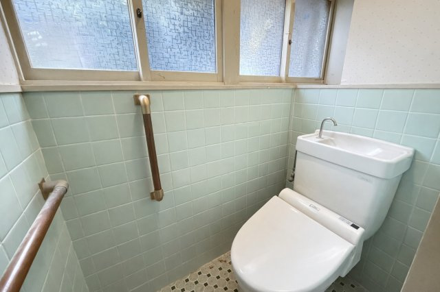 清潔感のあるトイレ空間は、窓付きで明るく換気もしやすい設計です。手すりが設置されており、どなたでも安心してご利用いただけます。玄関近くに配置されているため、来客時にも使いやすい動線です。