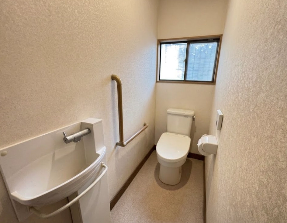 窓付きで明るく換気もしやすいトイレ空間。手すりが設置されているため立ち座りも安心です。手洗いも備わっており、使い勝手の良い設計です。シンプルながら機能性を備えた、日常使いに便利なトイレとなっています。