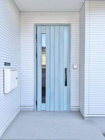 淡いターコイズブルーの玄関ドアが目を引きです。　玄関ポーチの屋根が雨風を防いでくれます。