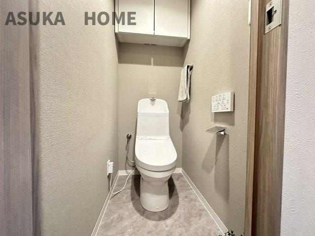 温水洗浄便座のトイレ設備です。奥行きの有る、棚も設置されるゆったりしたスペースのトイレ空間です。