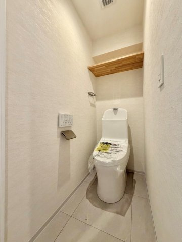 トイレットペーパーのストックや掃除用具を生活感を出さずに収納できる、便利な上部吊戸棚付き。限られたスペースを最大限に広く、美しく使うための嬉しい工夫が施されたクリーンな空間です。