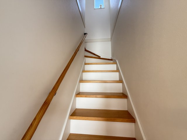 木の踏板と手すりが温かみを感じさせる階段。窓から自然光が差し込み、日中は明るい空間です。ストレートに上がる形状で上り下りがしやすく、手すり付きで安全面にも配慮。毎日の移動も安心して行えます。　