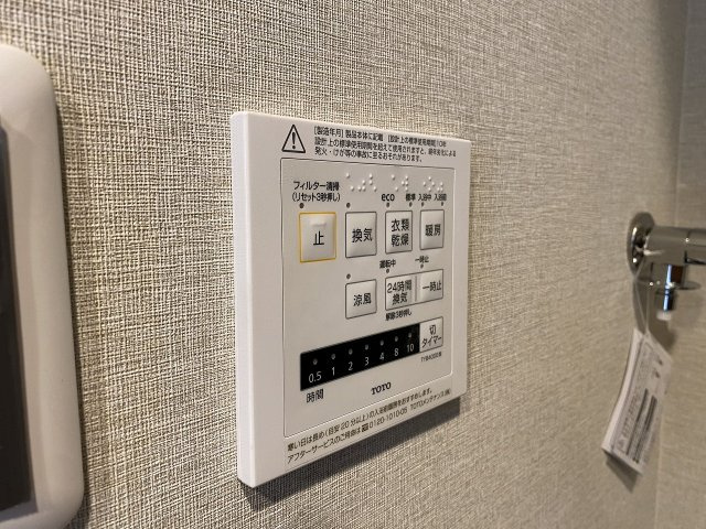 浴室暖房換気乾燥機のリモコンパネル。ワンタッチで雨の日の衣類乾燥や冬場の予備暖房、夏の涼風機能などを簡単に切り替え可能です。日々の家事を効率化し一年中快適なバスタイムを支える先進の設備となっています。