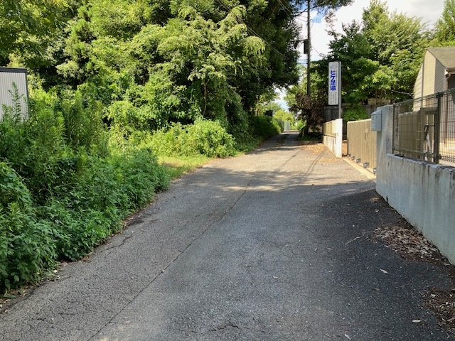 土地の接している北西側道路から北側へ向かうと、道路の入口があり、東西の道路と接しています。その道路の東側から西へ向かって撮影しました。
