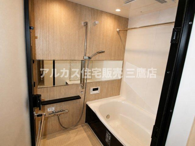 温かみのある木目調パネルと横長ミラーがリラックス空間を演出する、浴室換気乾燥機付きバスルーム。
