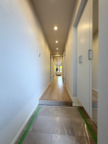 玄関を開けると、奥のリビングまで視線が心地よく抜ける開放的な廊下空間。天井のダウンライトが足元まで優しく照らし、住まい全体の洗練された雰囲気を印象付けます。