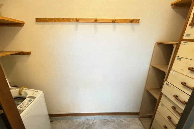 室内に洗濯機置き場を確保した洗濯スペースです。壁面にはフックや棚が設けられており、洗剤や小物類の整理にも便利です。独立した空間となっているため、家事動線をまとめやすい点が魅力の空間です。