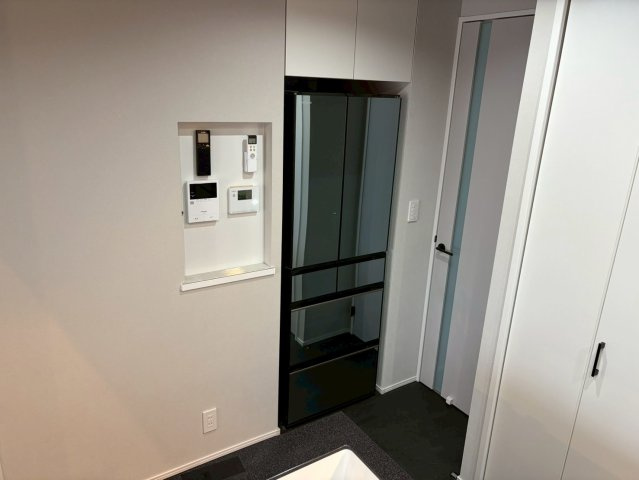 キッチン背面には冷蔵庫や収納をすっきり収められるスペースを確保。白と黒のコントラストが美しく生活感を抑えたスタイリッシュな印象に仕上がっています。給湯やインターホンなどの操作パネルを集約されています。