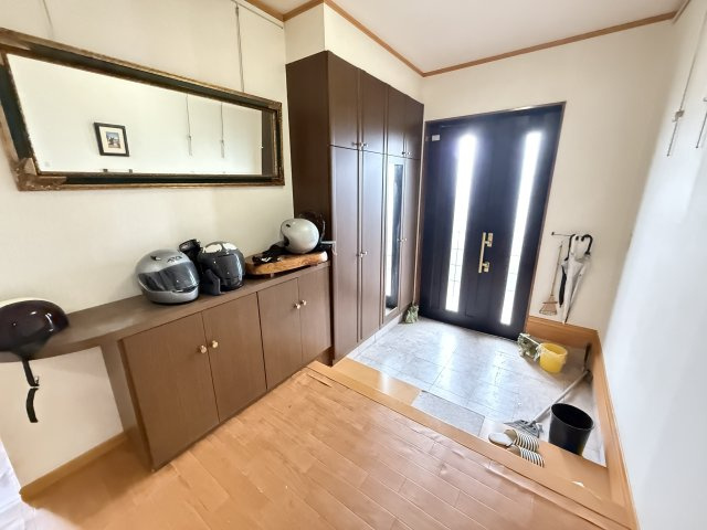 大きな鏡が設置された玄関は、外出前の身だしなみチェックに便利です。壁一面に配置されたシューズボックスは収納力が高く、靴だけでなく季節物や小物もすっきり整理可能です。玄関全体がきれいに保てます。
