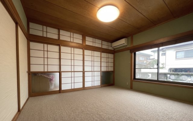 大きな窓から自然光が差し込む明るい和室で、障子や木の風合いが落ち着いた雰囲気を演出します。収納スペースも確保されており、寝室や客間、お子様のお昼寝スペースなど多彩な用途で活躍します。