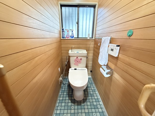木目調の壁が温かみを感じさせるトイレ空間です。小窓から光と風を取り込み清潔で快適な使用環境を保ちます。温水洗浄便座付きで機能性も充実。シンプルながら落ち着いた雰囲気で毎日の利用に安心感を与えてくれます