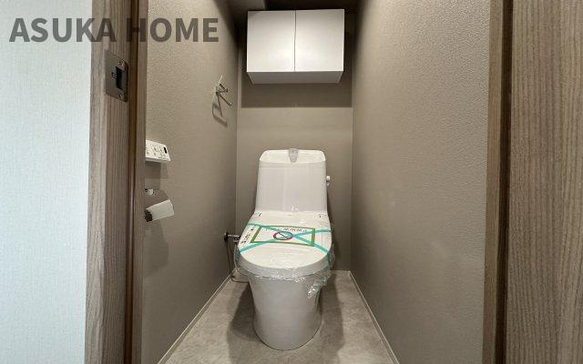 温水洗浄便座のトイレ設備です。トイレ上部にはあると便利な吊戸棚やタオル掛けを設置。
