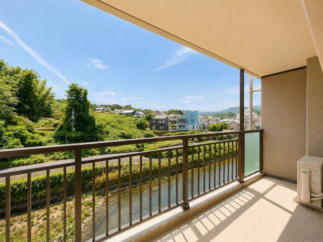 バルコニーからは、開放感ある景色を楽しめます。目の前には緑豊かな自然が広がり、日々の暮らしの中で季節の移り変わりを感じられる住環境です。川沿いの穏やかな景観と自然に囲まれて、心地よい時間を過ごせます。