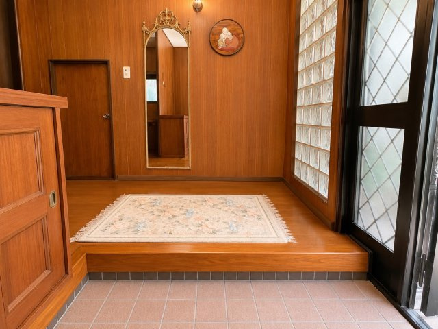 木目を基調とした温かみのある玄関空間が来訪者をやさしく迎えてくれます。ゆとりある広さに加え鏡付きでお出かけ前の身だしなみチェックにも便利。重厚感ある内装デザインが住まい全体の上質な雰囲気を演出します　
