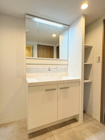 シャワー付き洗面台で朝の準備も掃除もスムーズ。3面鏡付きのミラーキャビネットの後ろは収納もあります