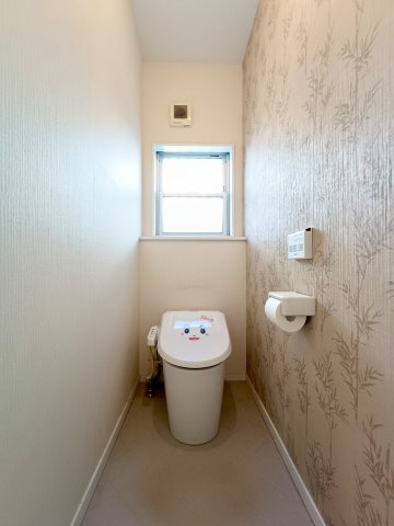 【1階トイレ】　シックな色合いのクロスが落ち着いた印象。