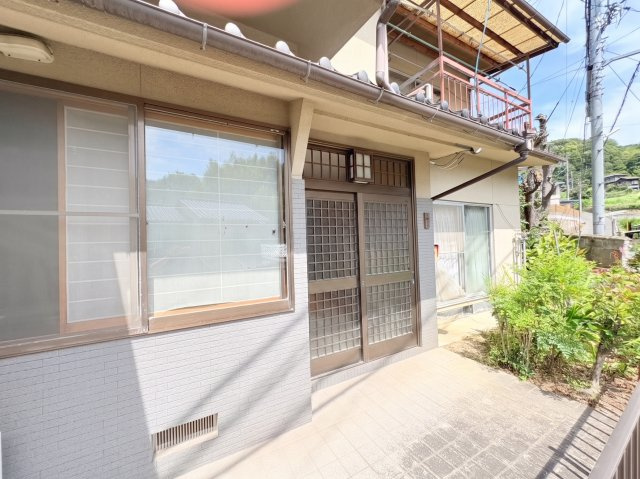 住まいの趣を感じさせる格子デザインの玄関が印象的です。玄関前にはゆとりのあるスペースが確保され、植栽の緑とともに落ち着いた雰囲気を演出。閑静な住宅街に馴染む、どこか懐かしさと温かみを感じさせる佇まい。