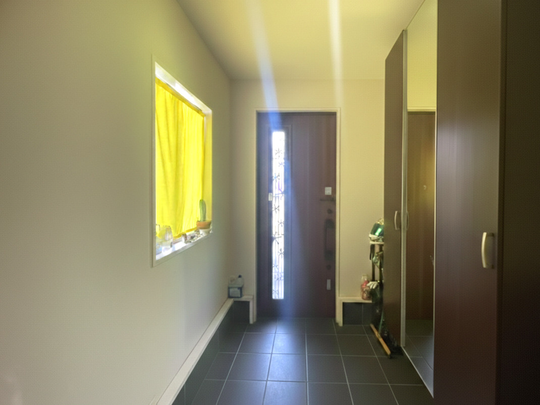 ゆとりある広さを確保した玄関スペース。窓から光が入り明るく、来客時にも好印象を与える空間です。収納力のあるシューズボックス付きで、靴や小物もすっきり整理可能。落ち着いた色合いの建具が上質さを演出。