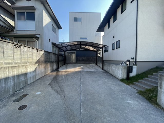 ゆとりある広い駐車スペース。カーポート付きで雨の日の乗り降りも快適。奥には物置もあり、タイヤやアウトドア用品の収納にも便利。前面の勾配も緩やかで駐車がしやすく、日常使いに優れた実用的な駐車場です。